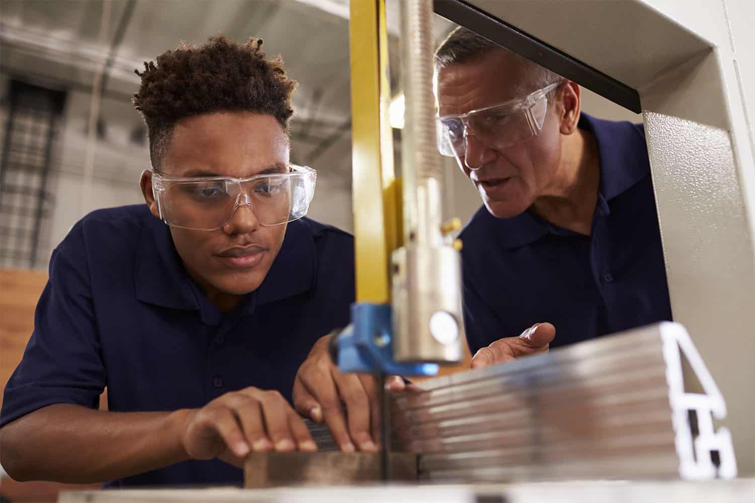 Apprentice cutting materials with a supervisor watching