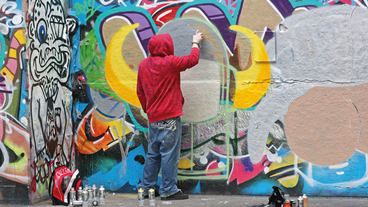 a guy wearing red hood painting a wall
