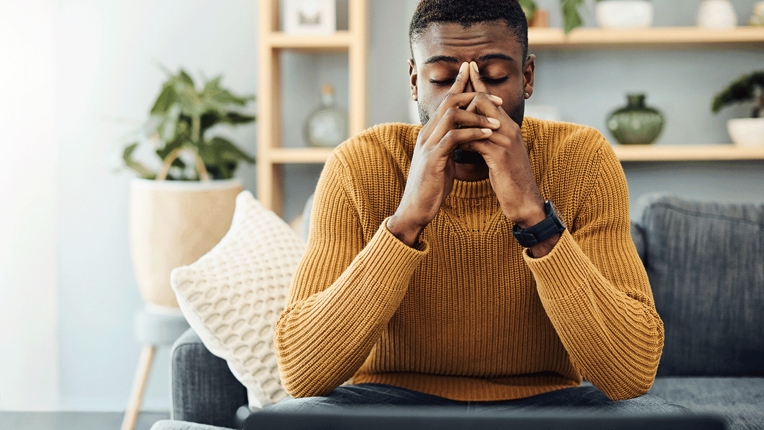 Man with his hands crossed in front of his face showing signs of stress