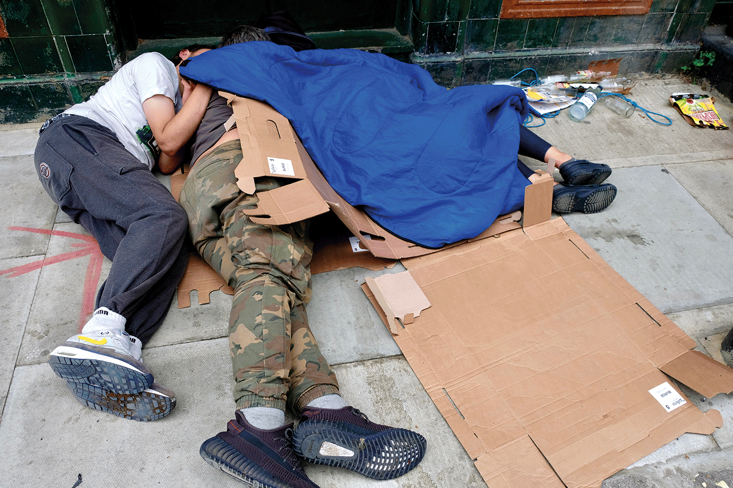 people sleeping on the streets covering themselves with cardboards