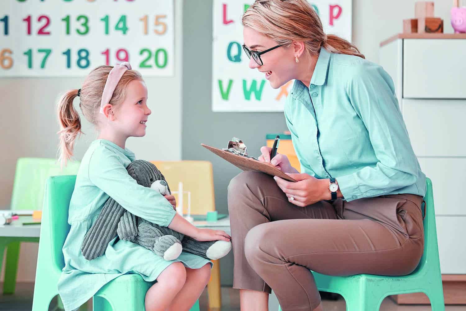 A support worker speaking with a young girl in a nursery
