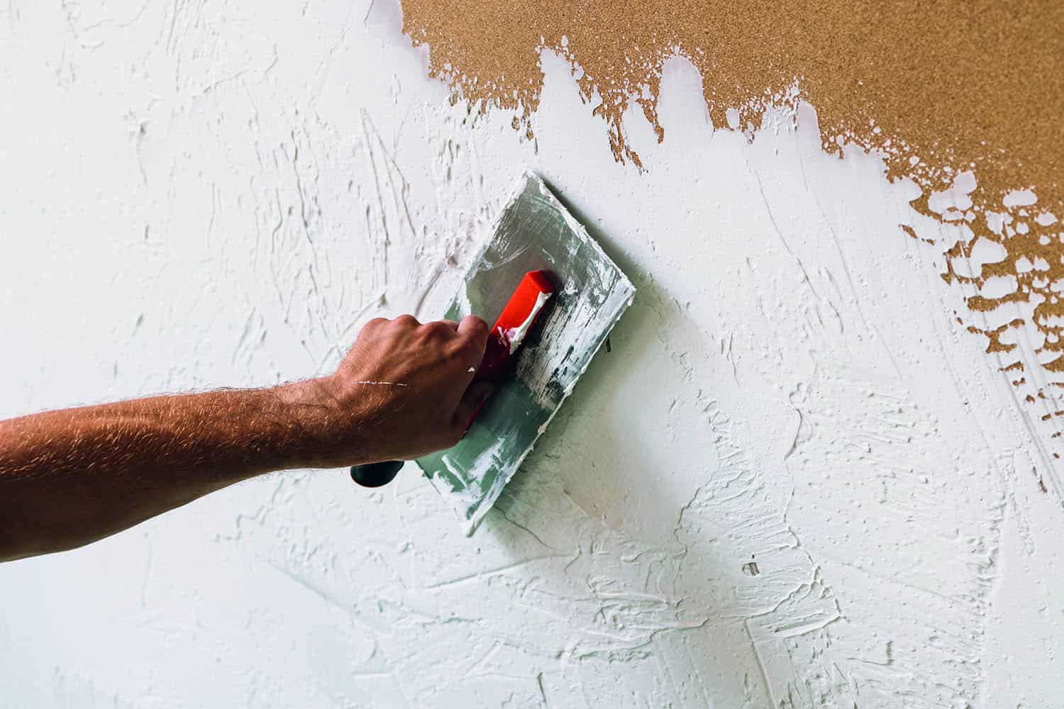 close-up of plaster’s hand smoothing over wall