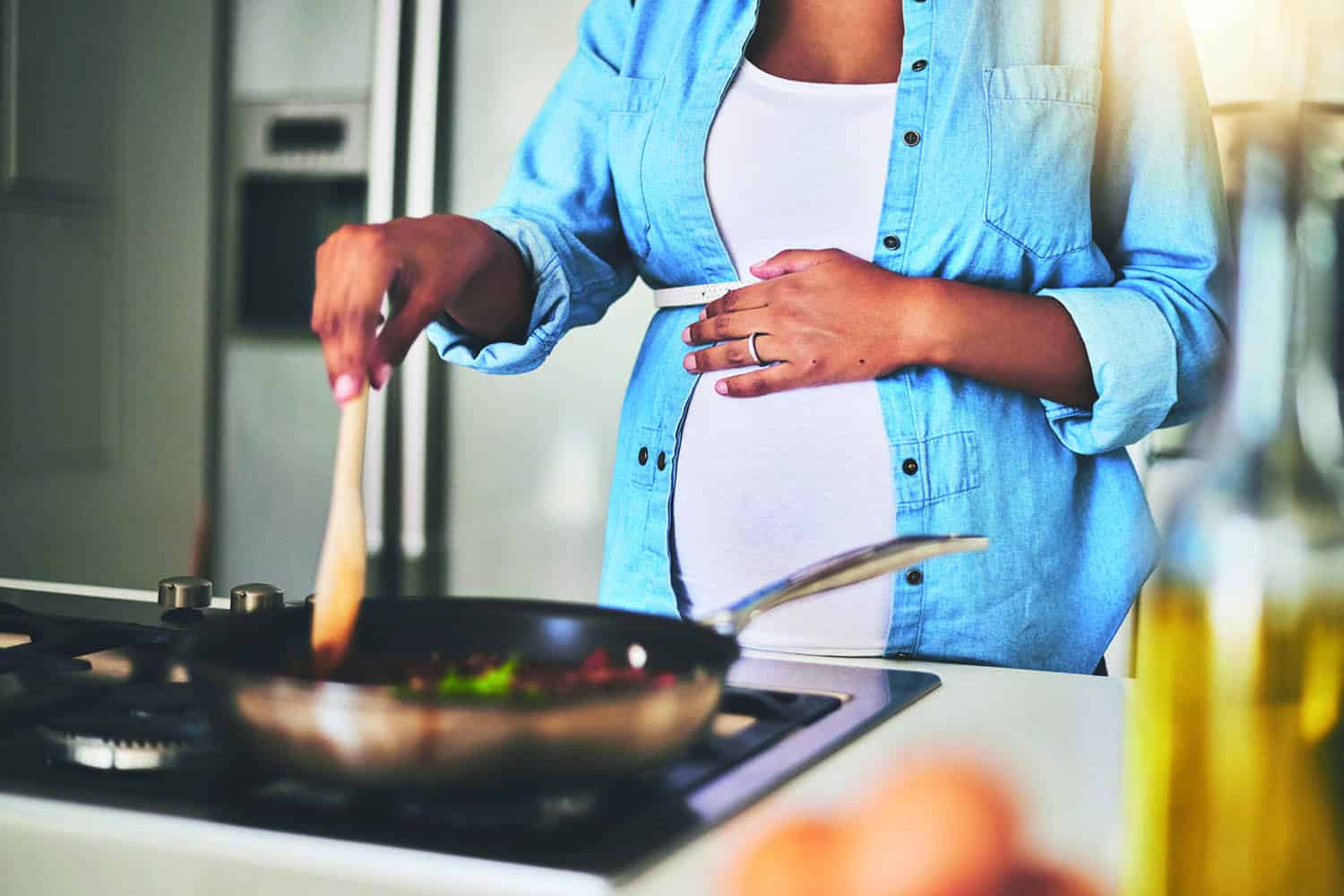 pregnant woman using frying pan on hob