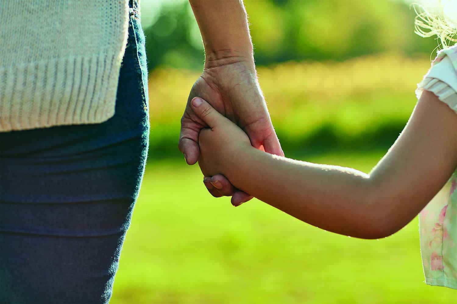 Close-up of adult hand holding child’s