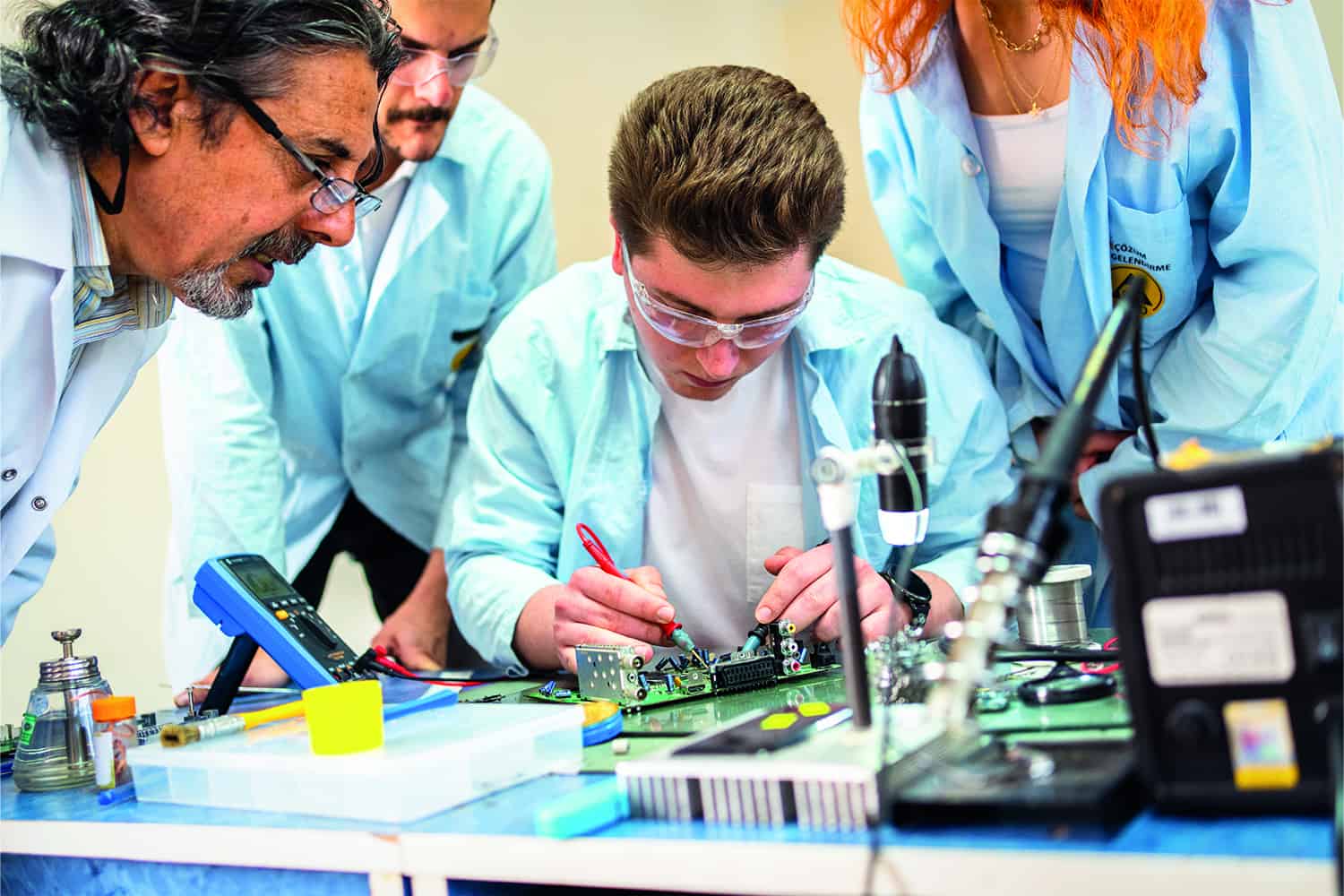 apprentices working on circuit board under supervision.