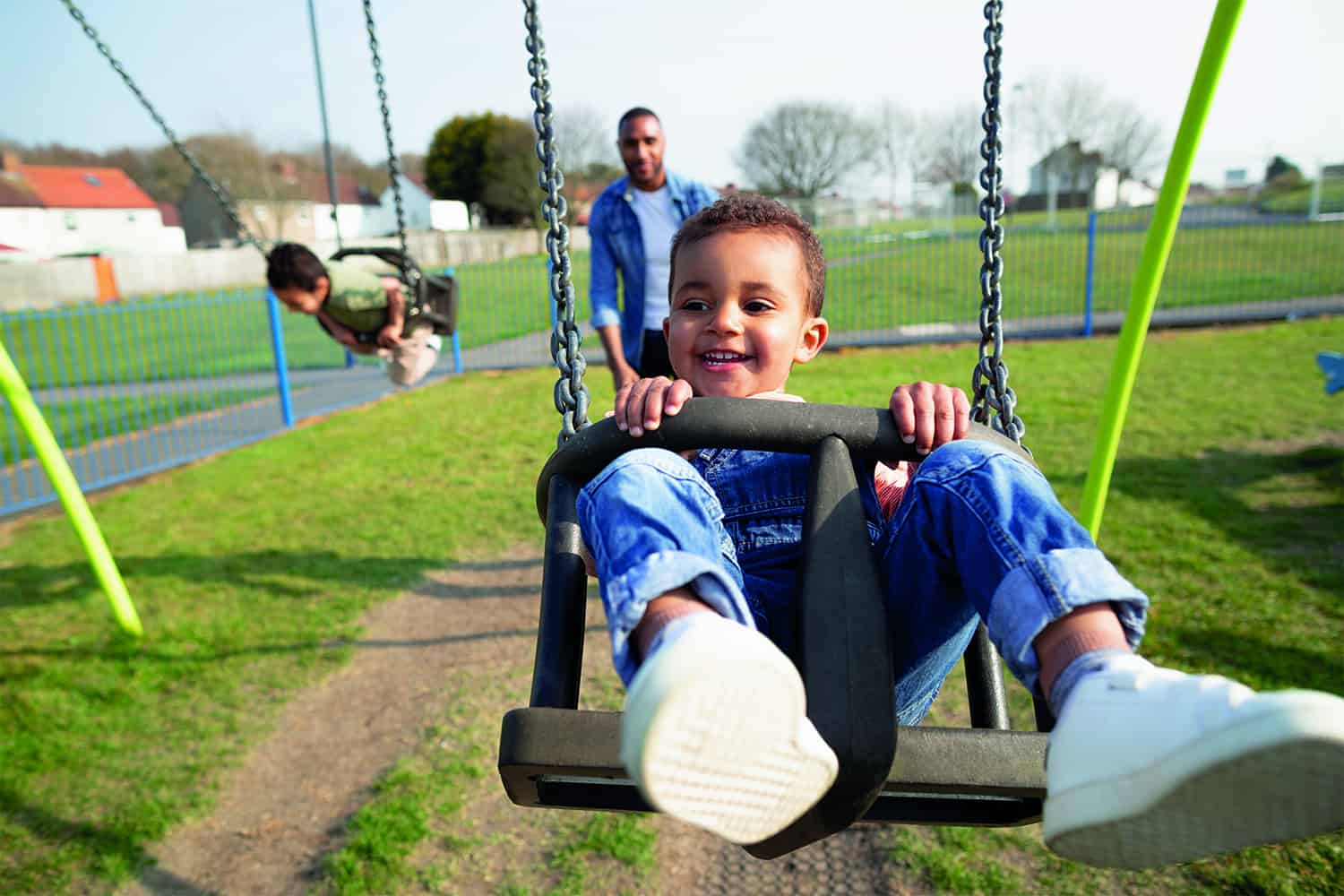 young boys being pushed in swings by father