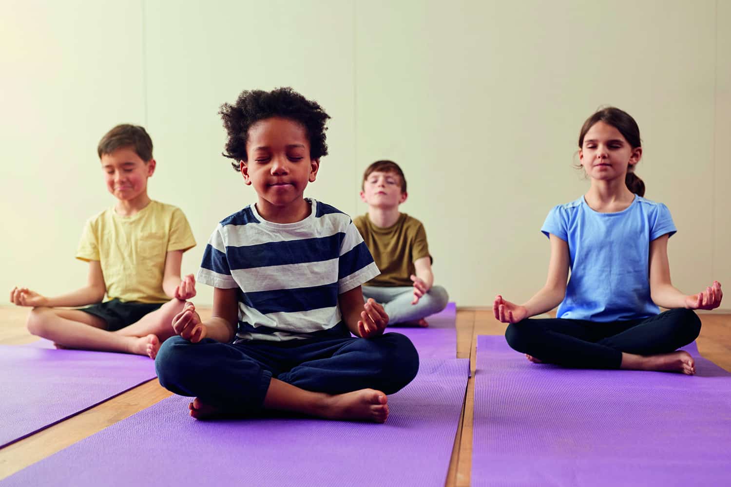 three young boys sitting in yoga position with eyes closed.