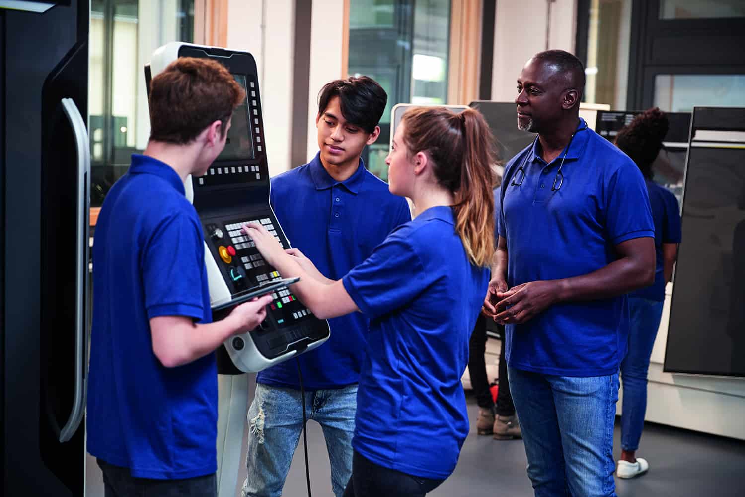 three young people using control panel in factory