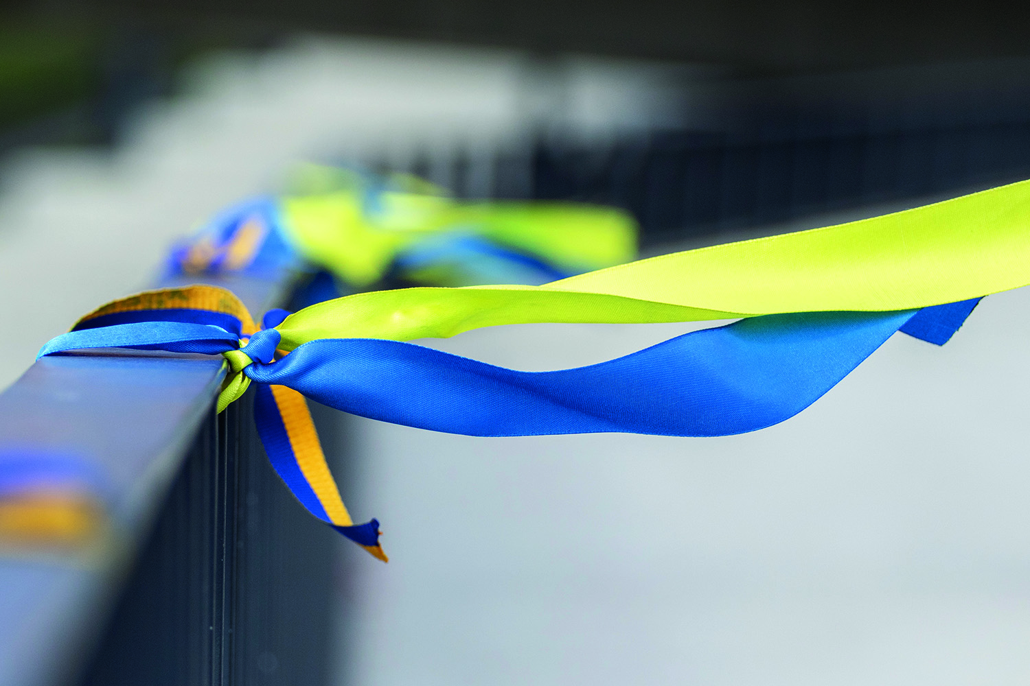 A ribbon in the colours of the Ukrainian flag tied around a railing.