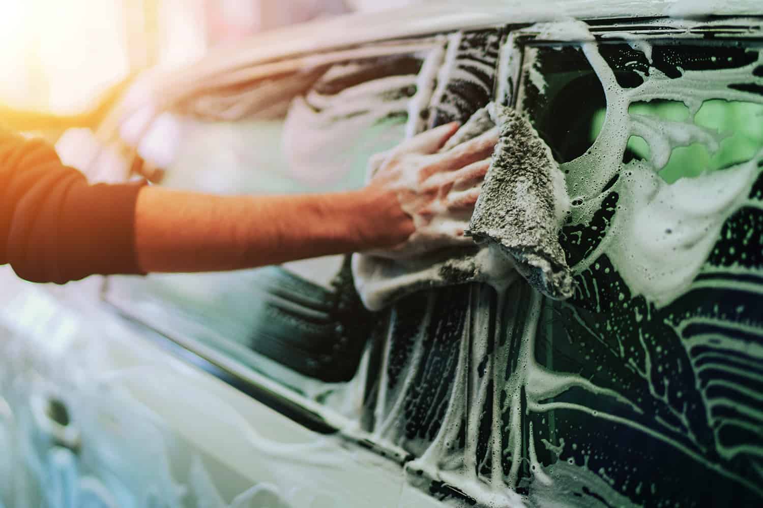 Hands washing a car.