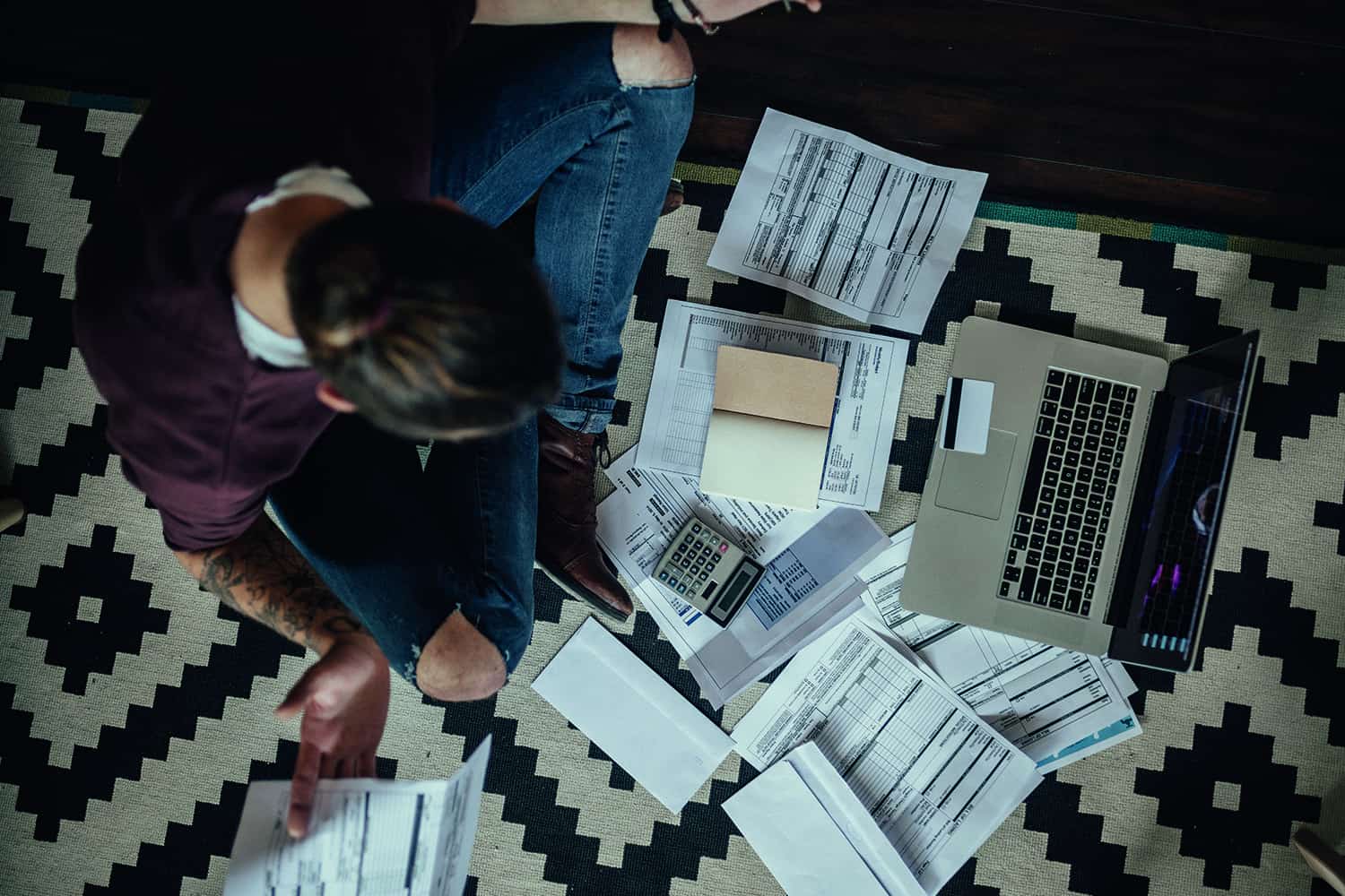 A young person studying with a laptop and many notebooks.