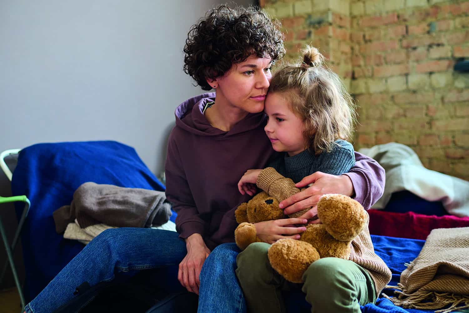 A woman sat on a bed with a little girl on her lap.