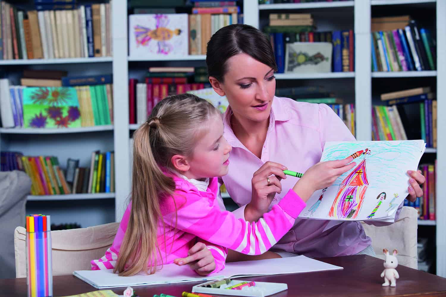 young girl showing drawing of home and family to care worker