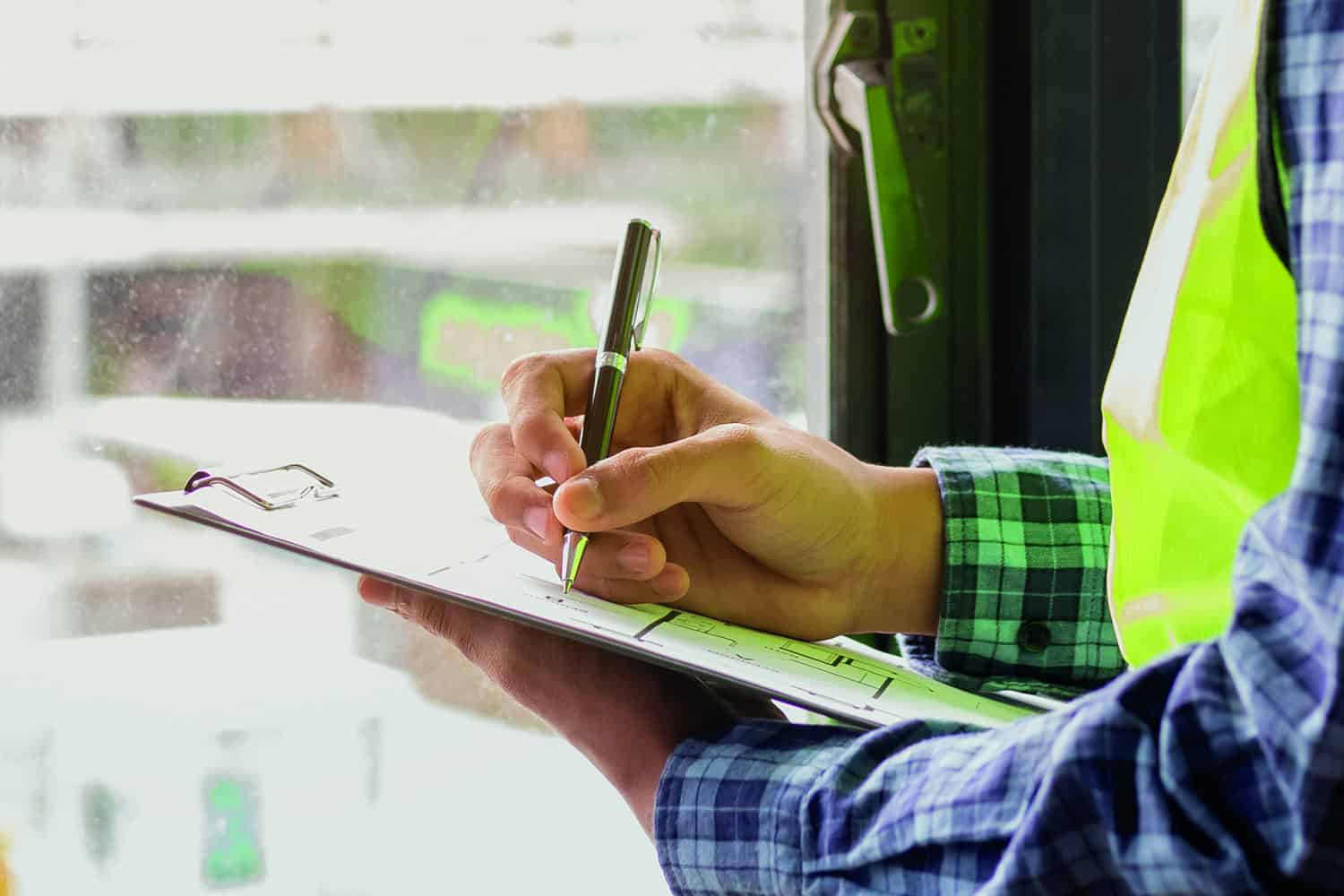 A man in a high-vis jacket writing on a clipboard