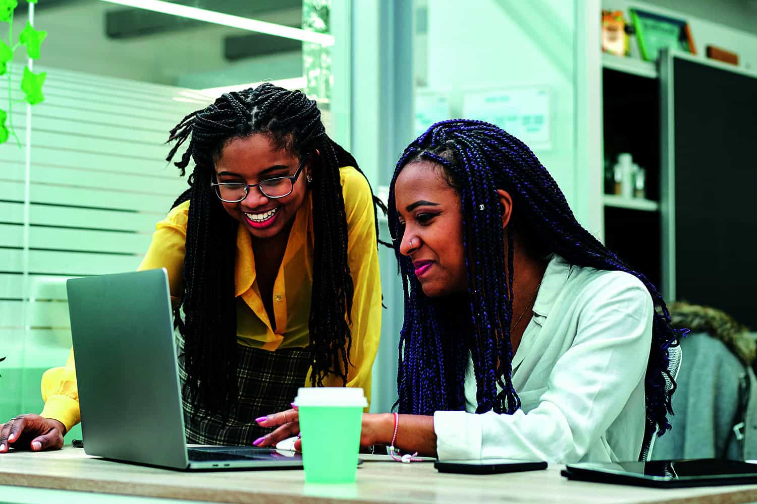 photo of two women looking at a laptop; graphic of celebrating figures