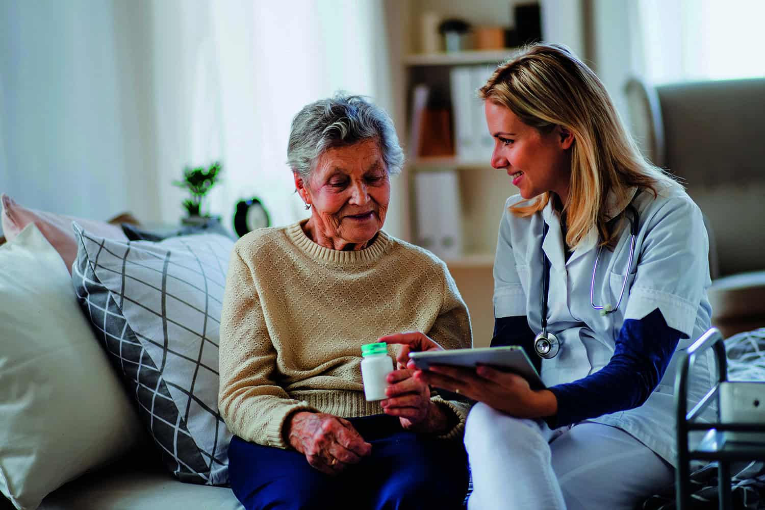 A carer helping an older woman with her medicine.