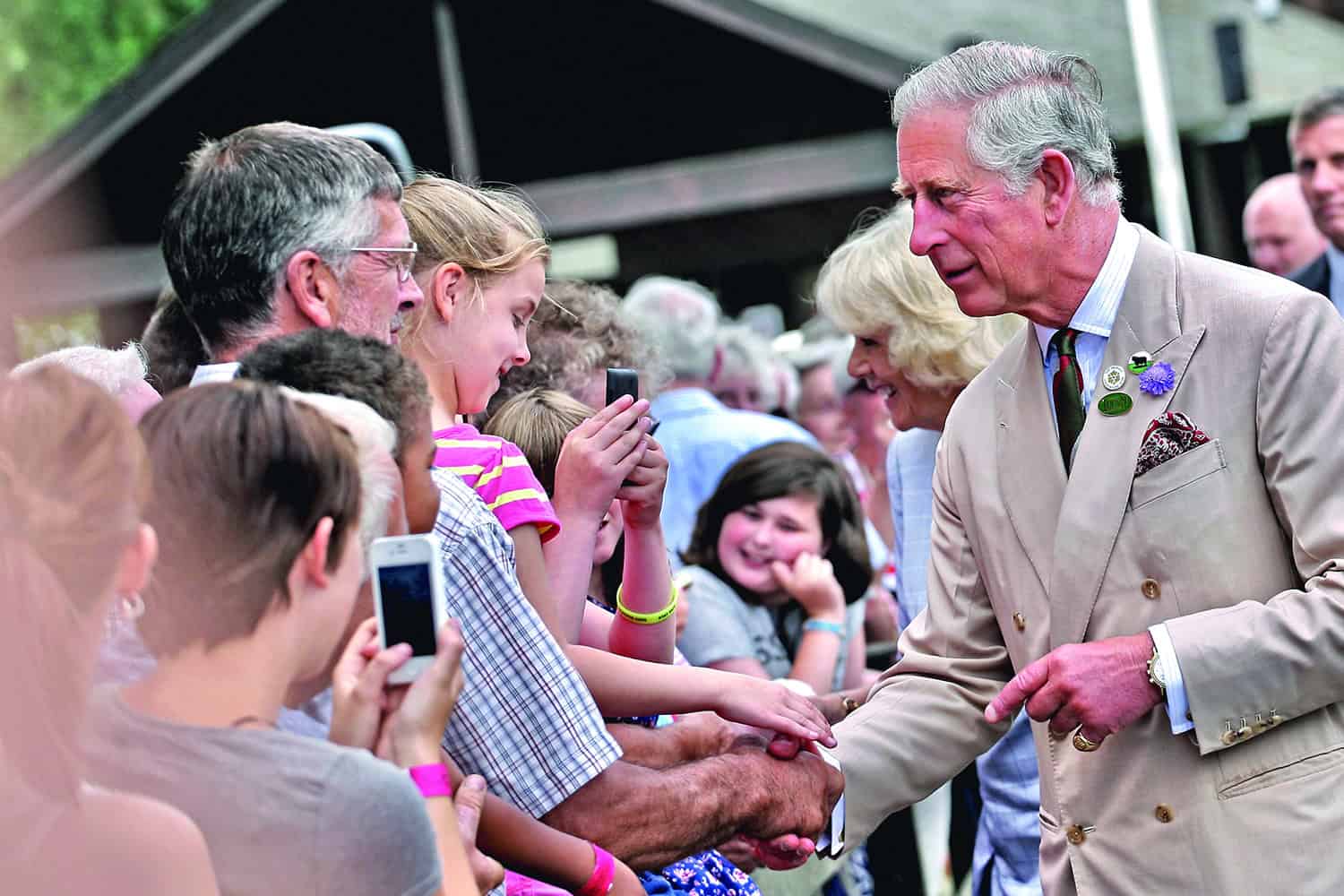 King Charles speaking with the public and shaking someone's hand.