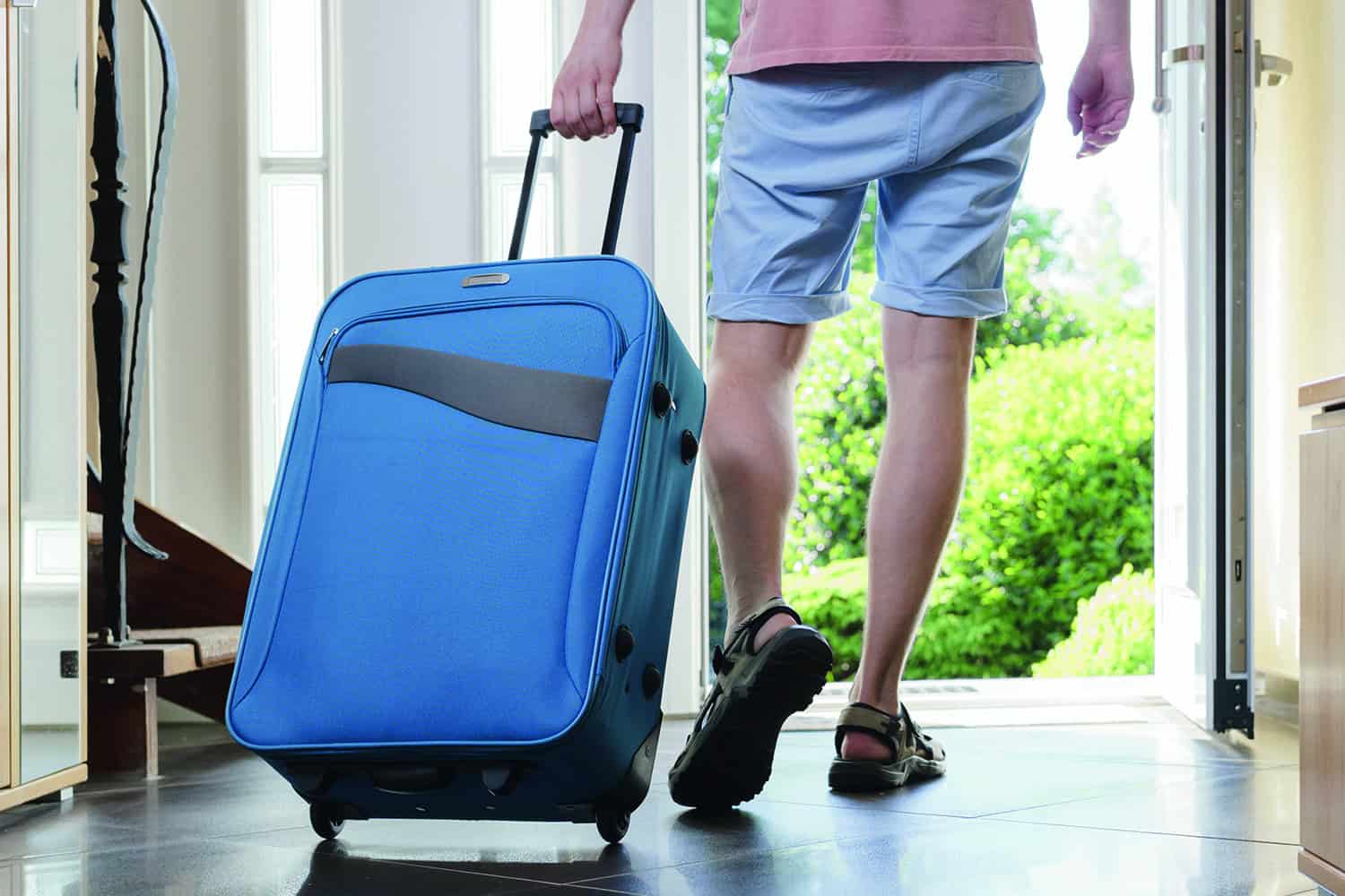 A man pulling a blue suitcase.