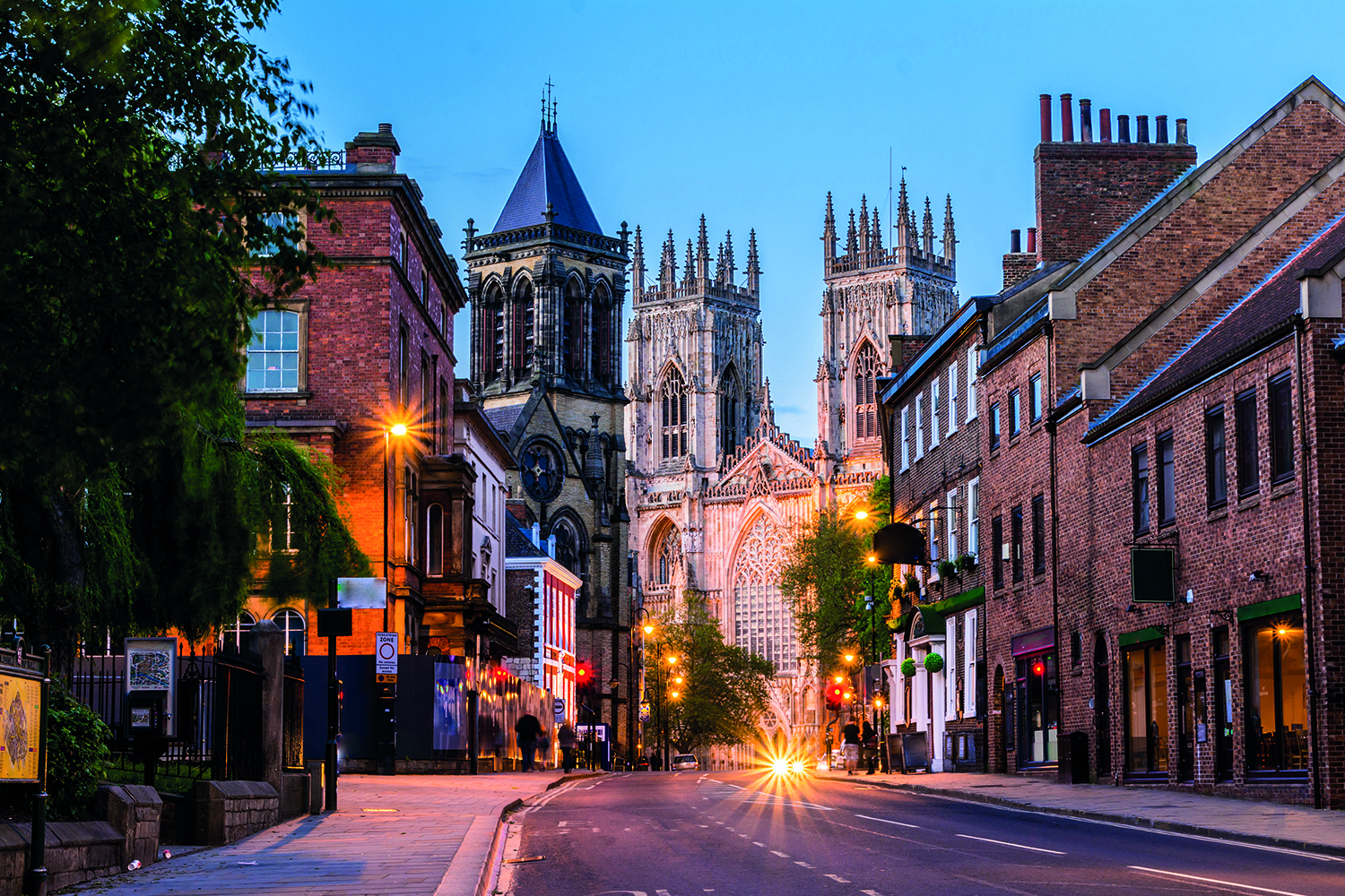 A town street at dusk with housing and a church