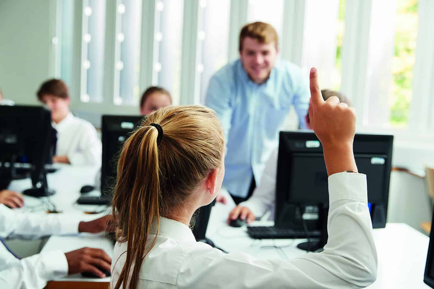 A schoolgirl raising her hand in the classroom.