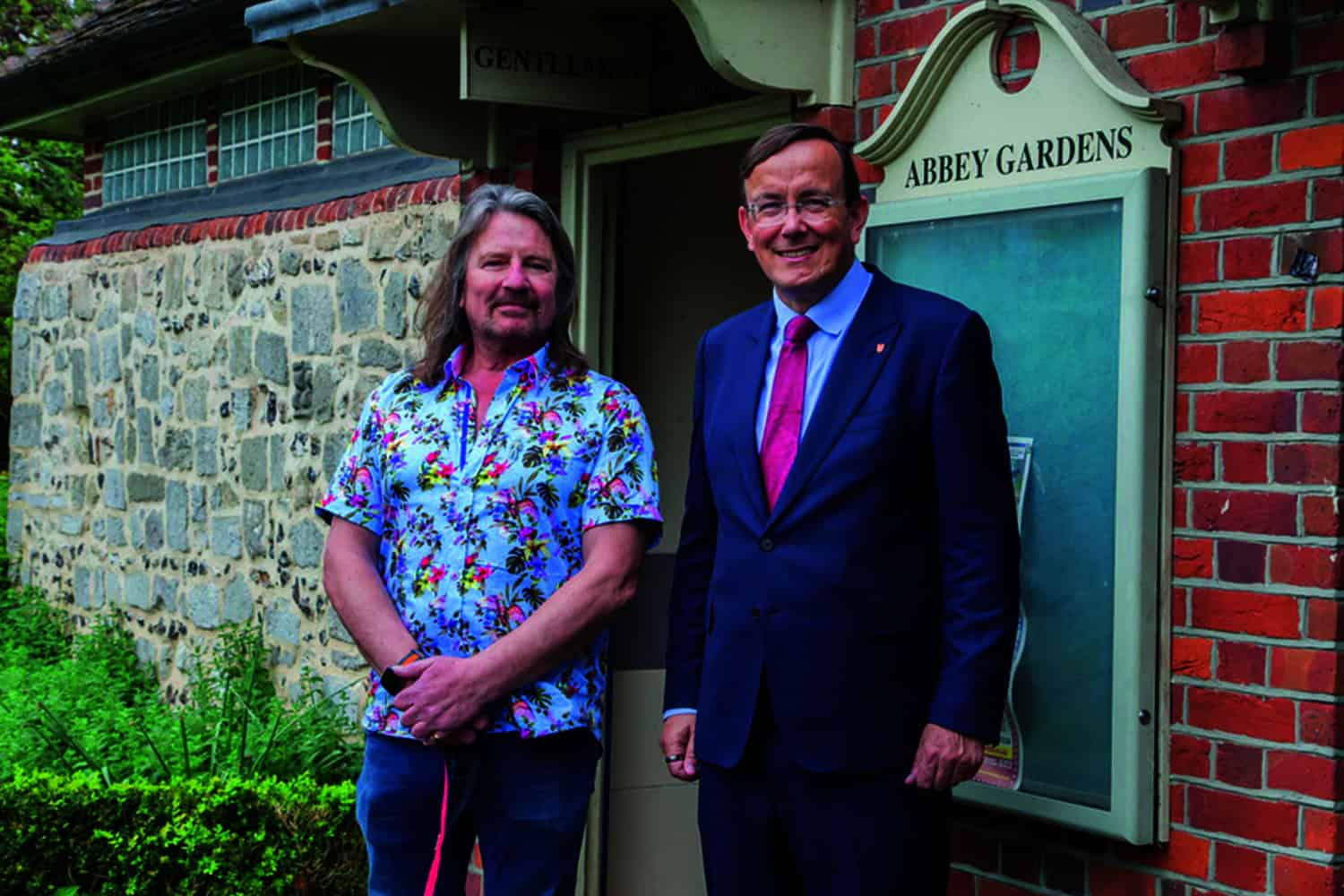 Councillor Martin Tod stood in suit alongside prostate cancer patient Jonathan Hall, outside a public men's toilet.