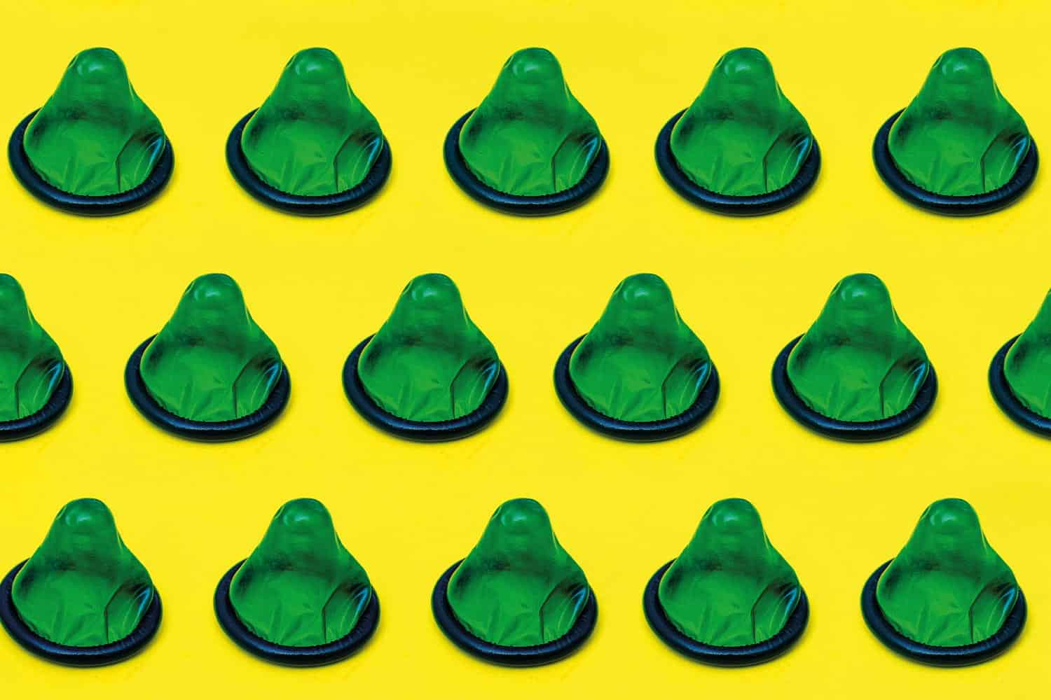 A number of green condoms on a yellow background.