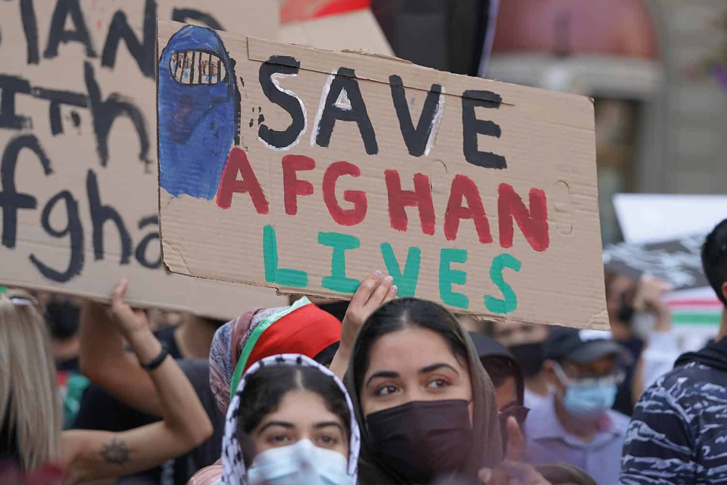 A cardboard sign being held up at a protest saying Save Afghan Lives