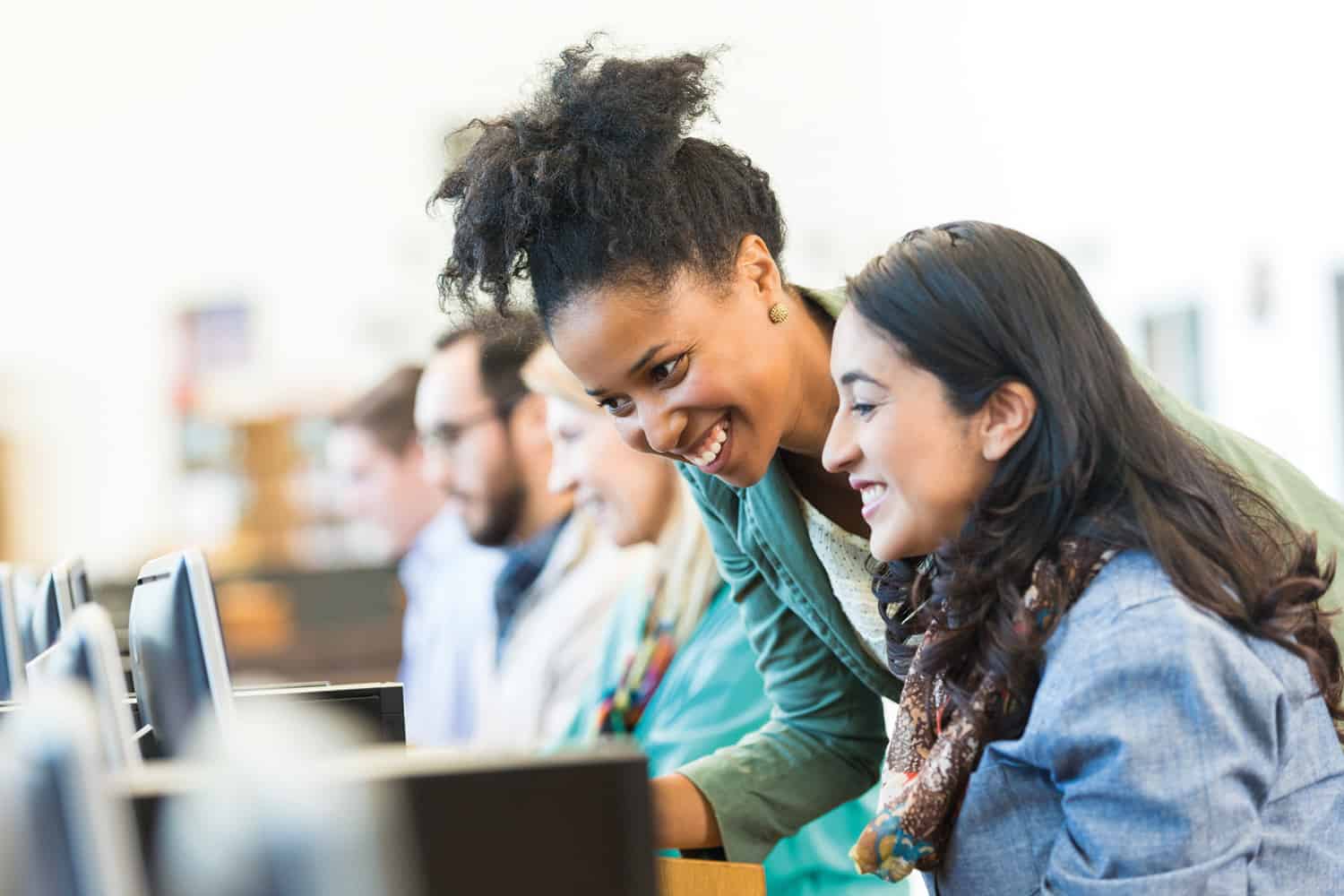 Two women smiling and looking at a laptop.