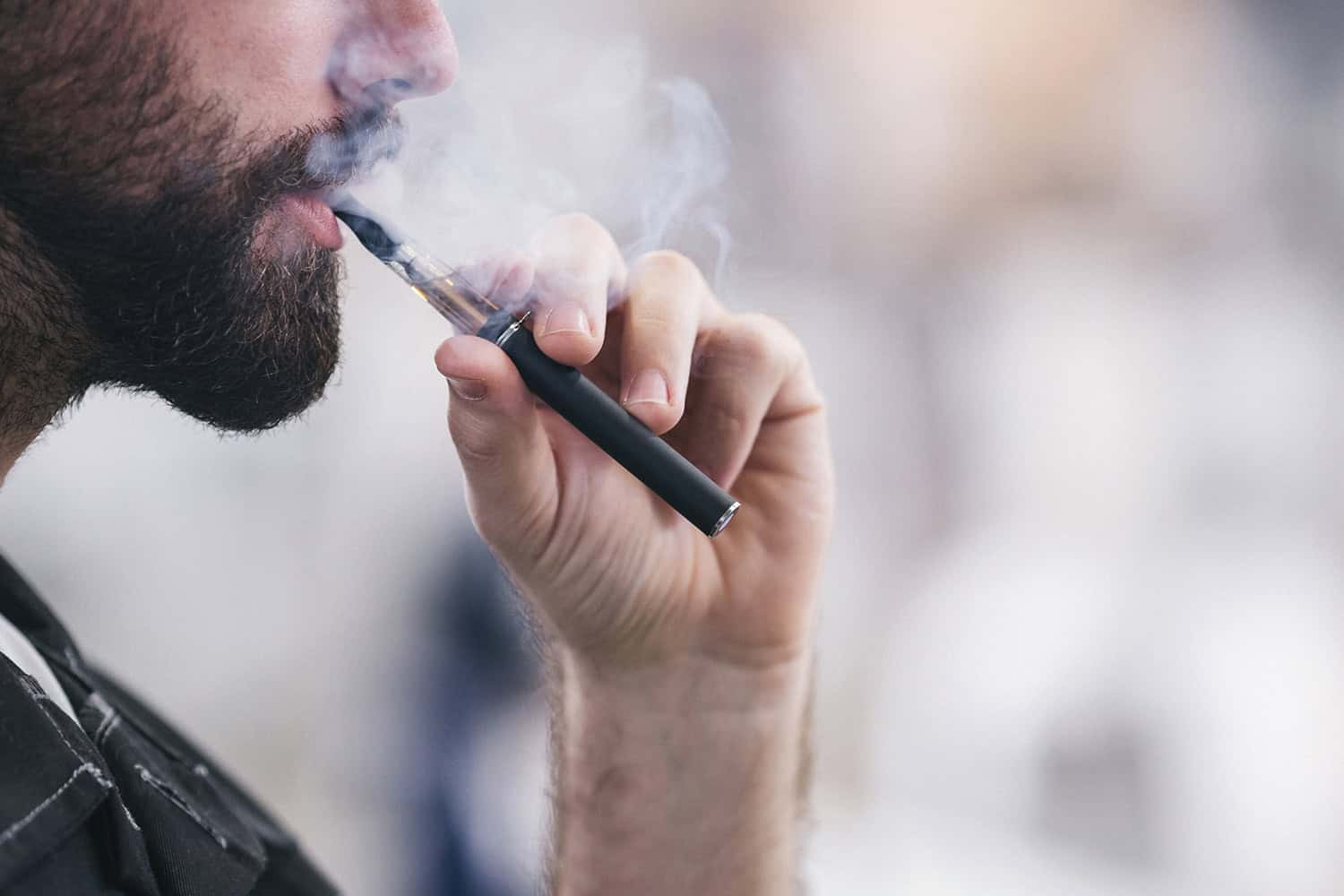 A man using a vape with his left hand.