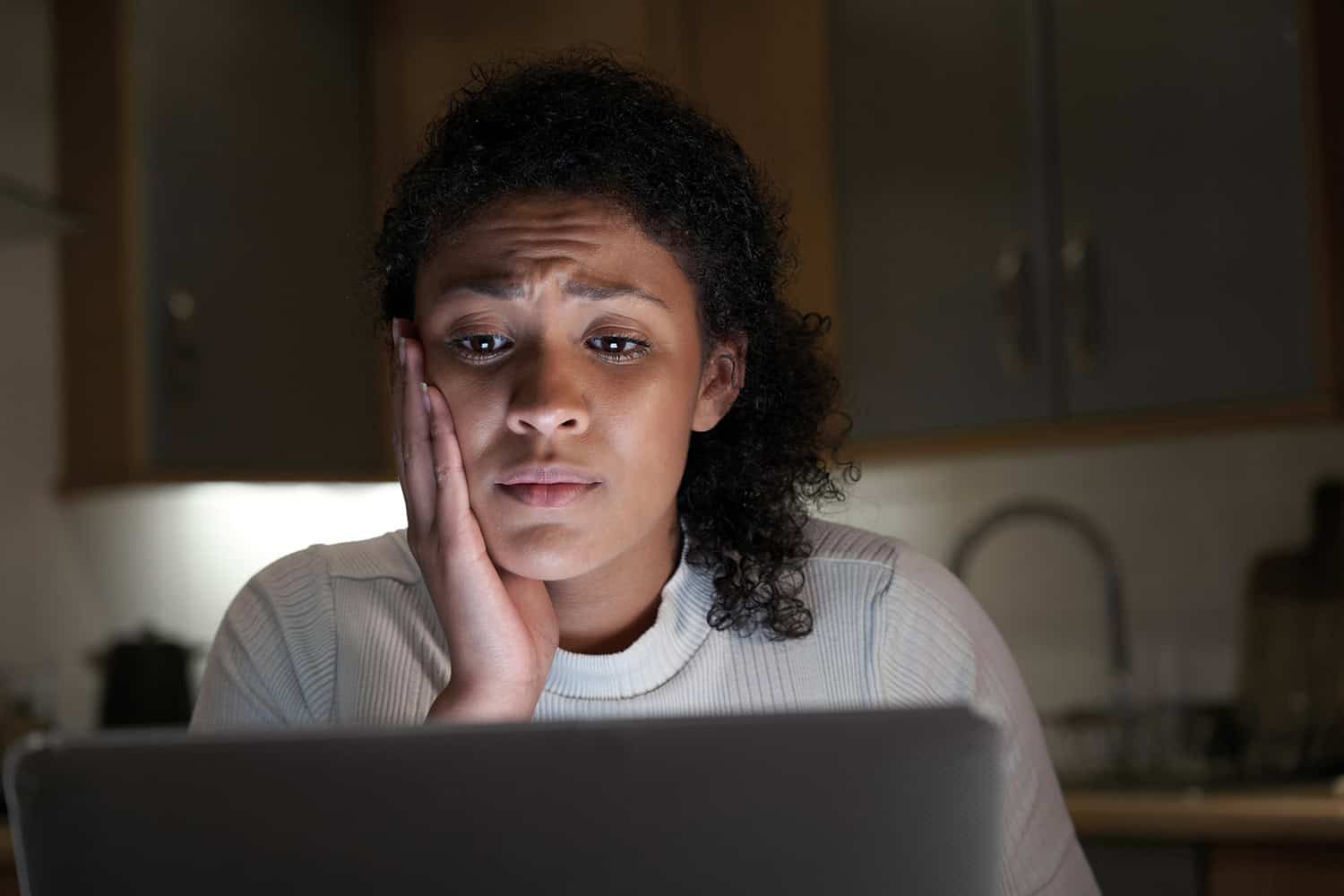 A woman looking worryingly at a laptop.