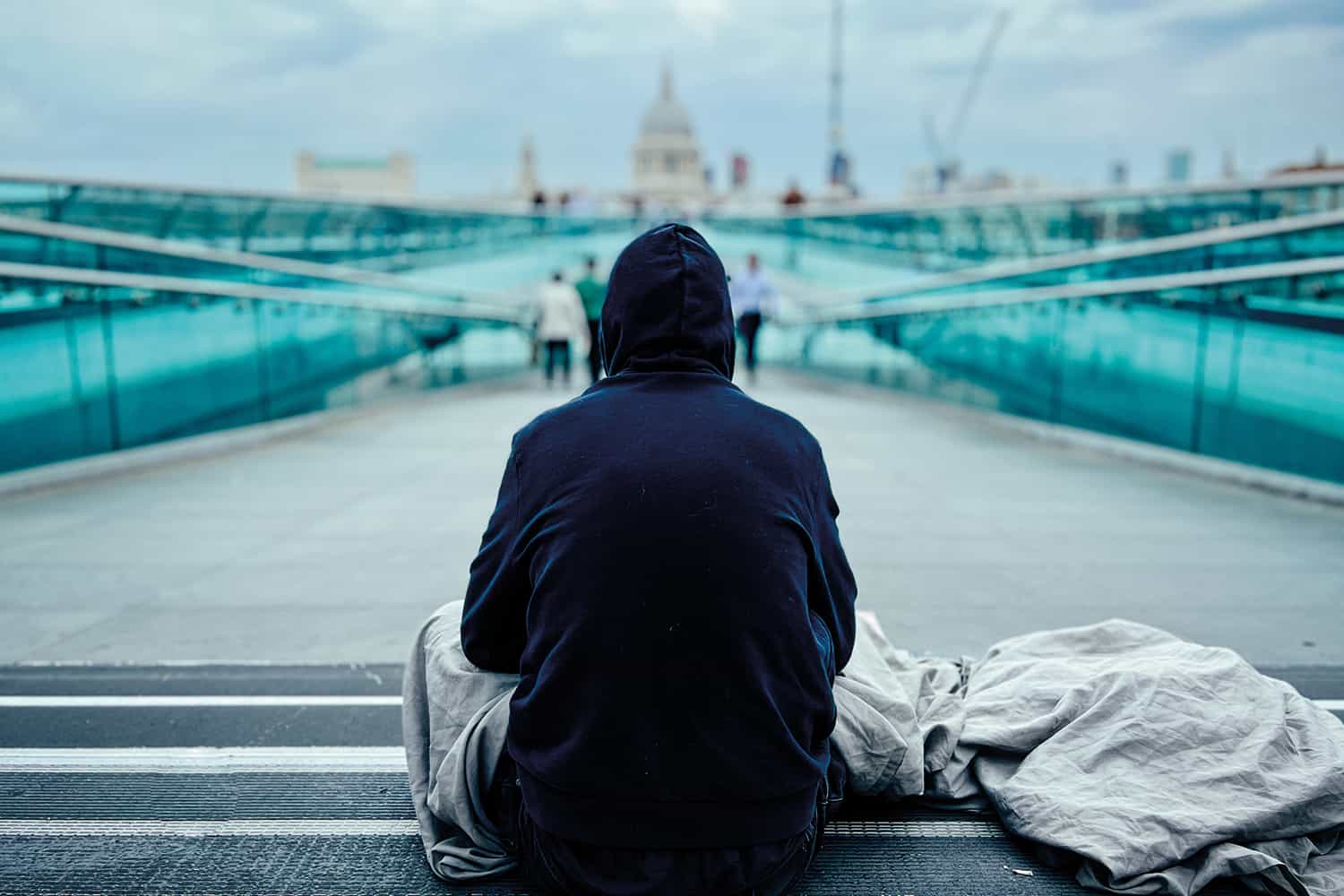 A homeless man sat facing Embankment bridge.