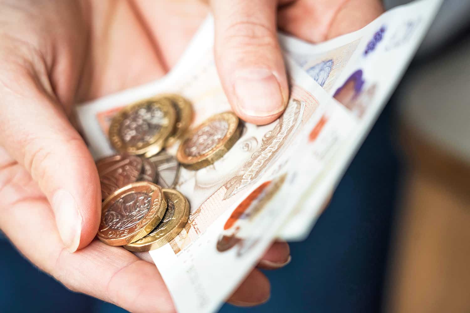 Paper money and coins held in two hands.