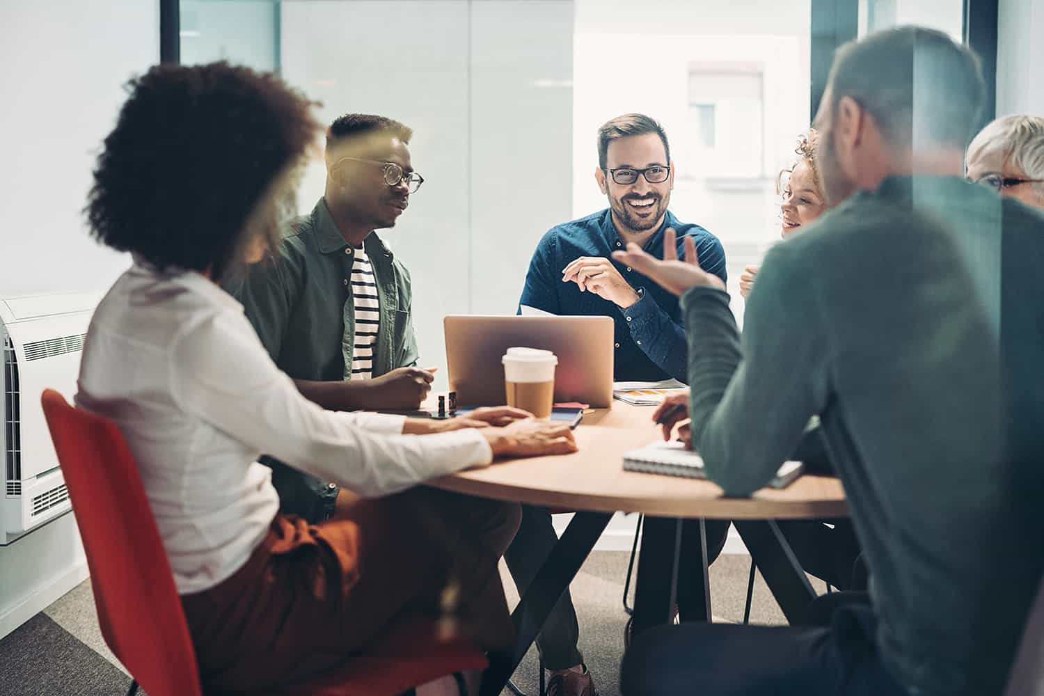 work colleagues in a meeting talking around a laptop