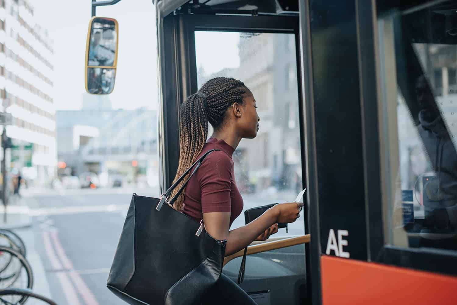 A black lady getting on a bus.