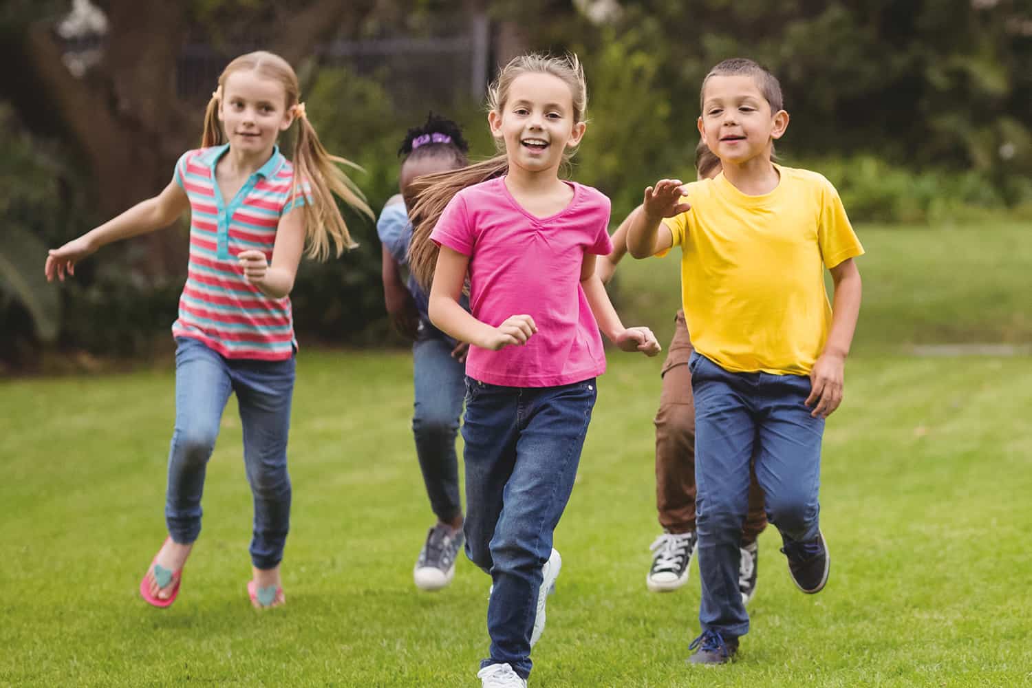 A group of young children running on a grassy area.
