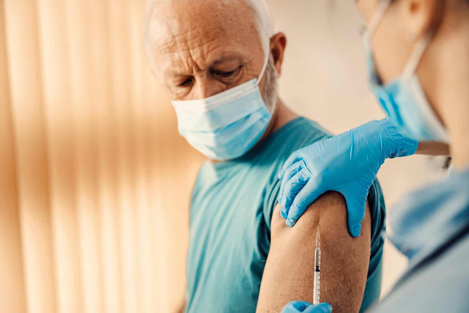 photo of older man in mask being vaccinated