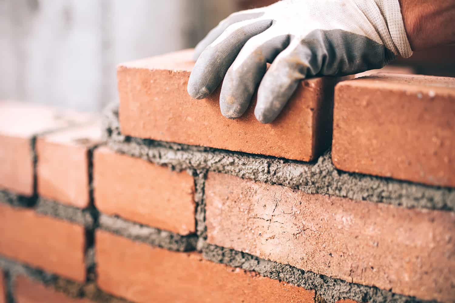 A bricklayer laying brick and cement.