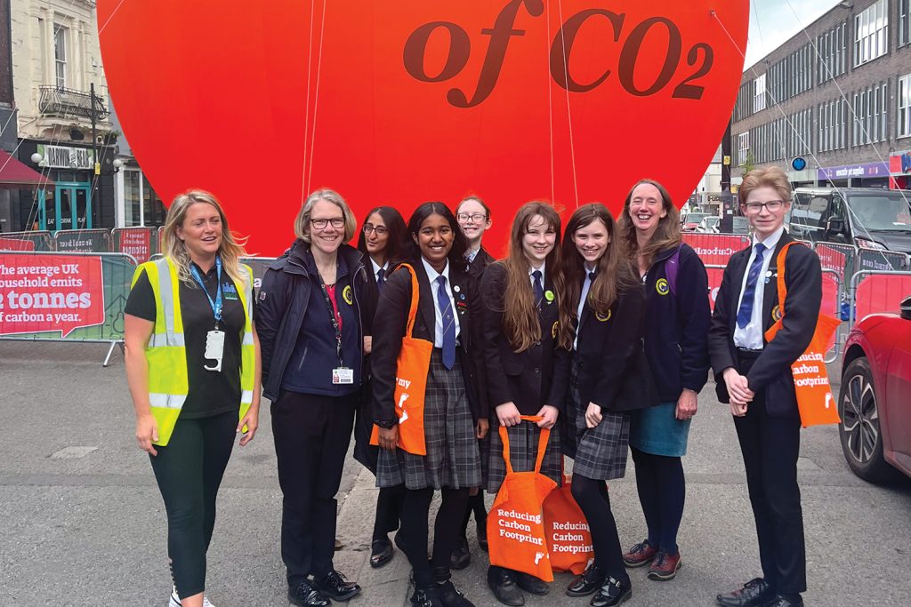 School pupils in front of a giant orange bubble containing a tonne o CO2