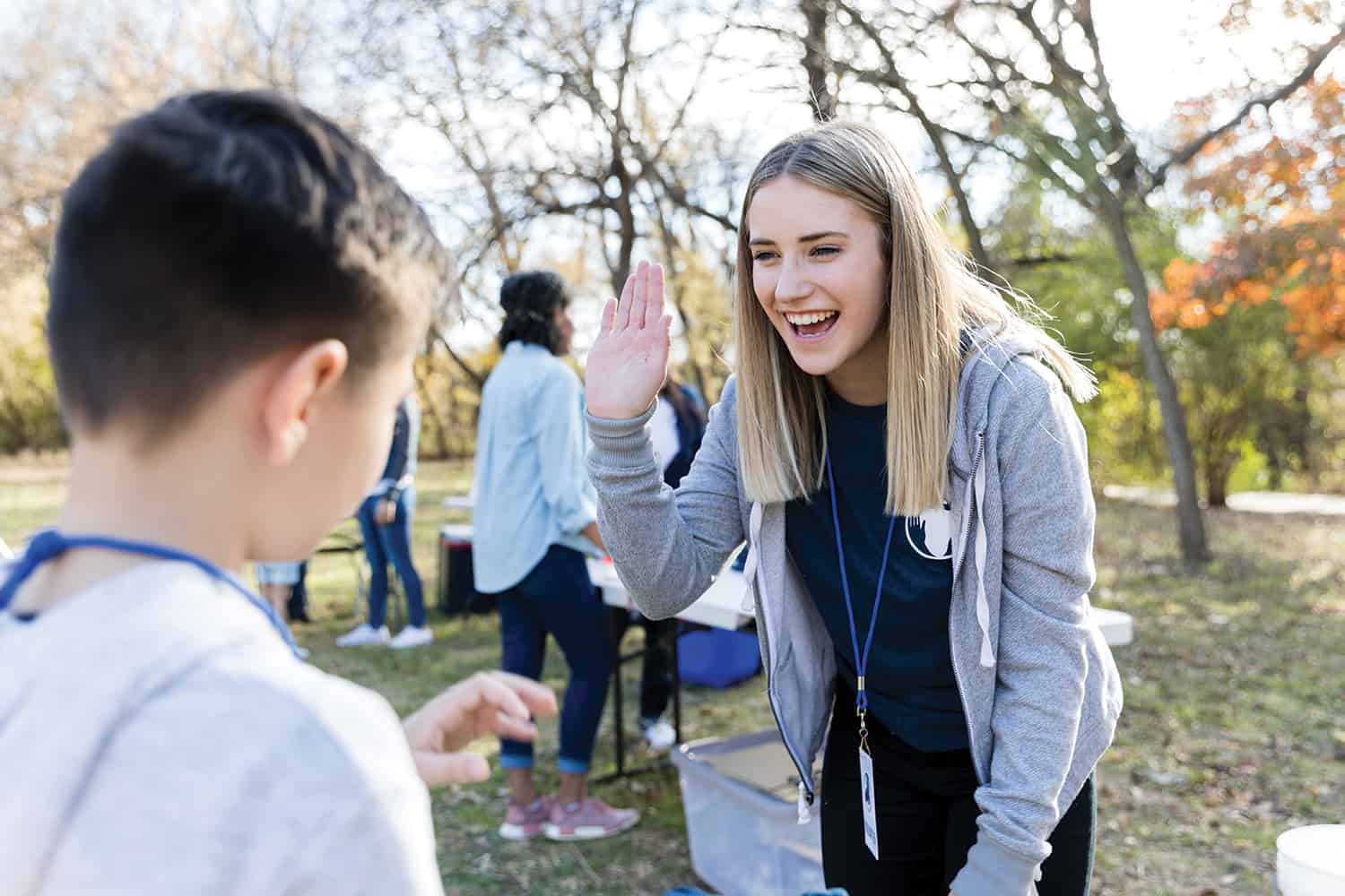 A care worker with hand raised, to high five to a young boy.
