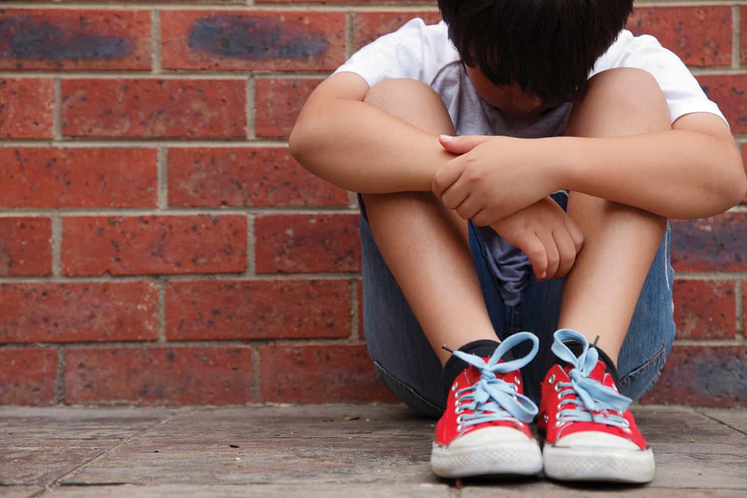 A young boy sat on the ground with his head bowed.