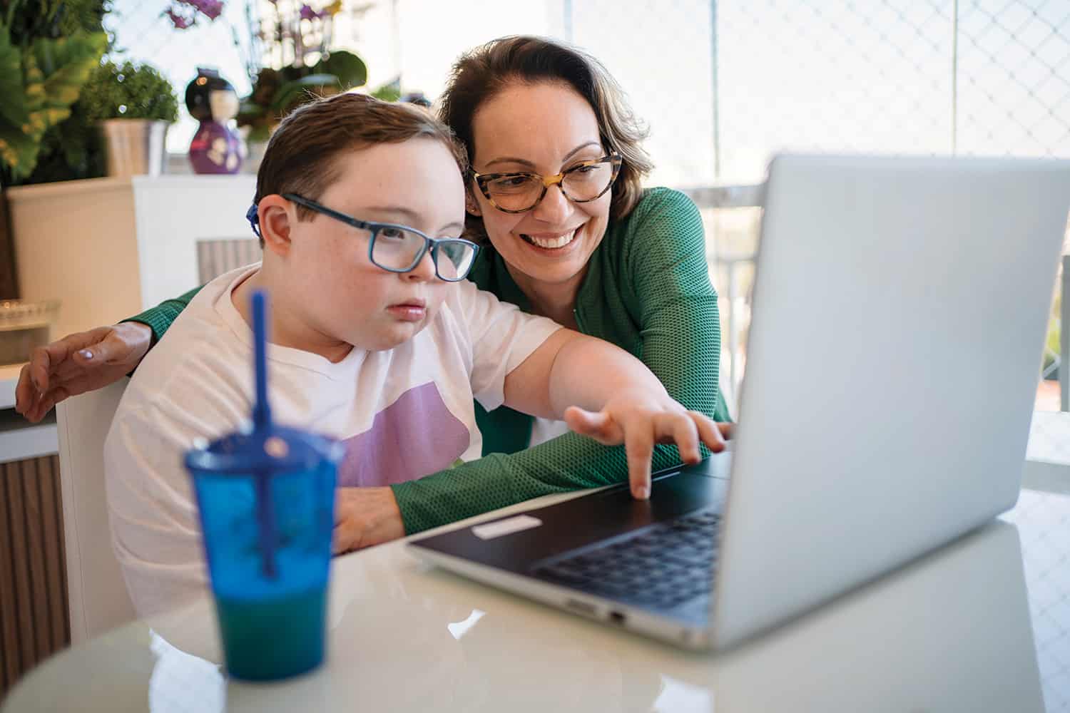 older woman helping boy with learning disabilities on a laptop