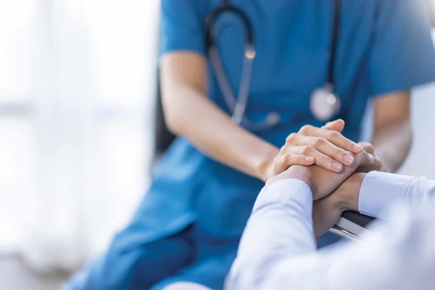 hand of female medic resting on hands of patient on arm of seat