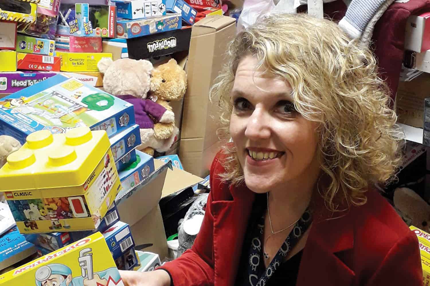 Policy Advisor Helen Walton smiling whilst next to the toys collected for Rochdale's Christmas Toy appeal