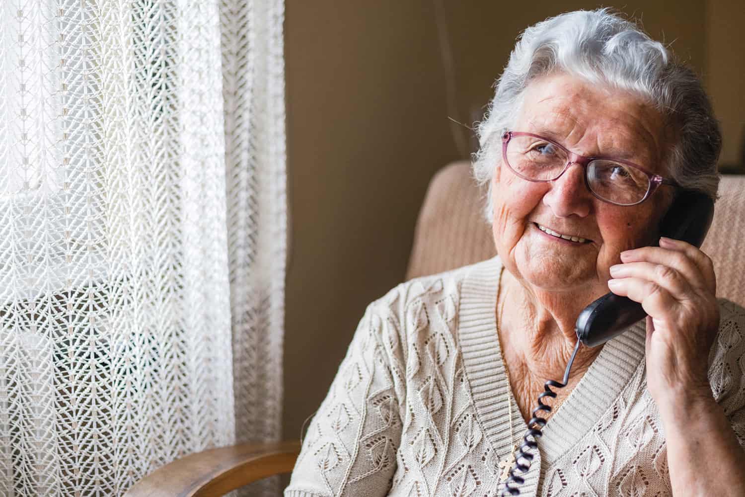 An elderly lady speaking on her landline phone
