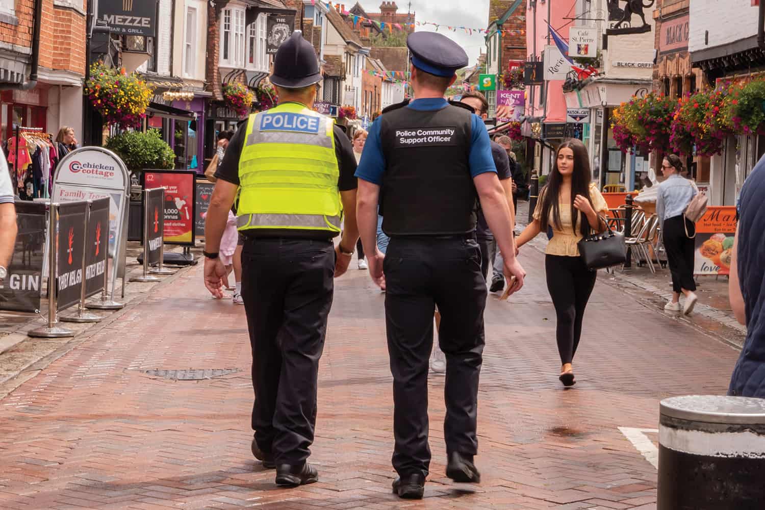 Two men walking down a local street in their police uniform