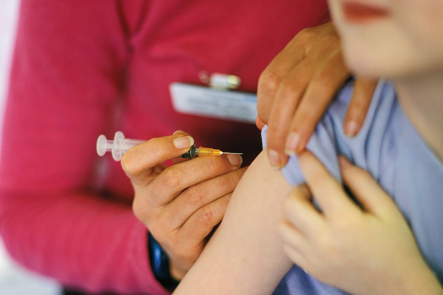 A lady injecting a child with a vaccine.