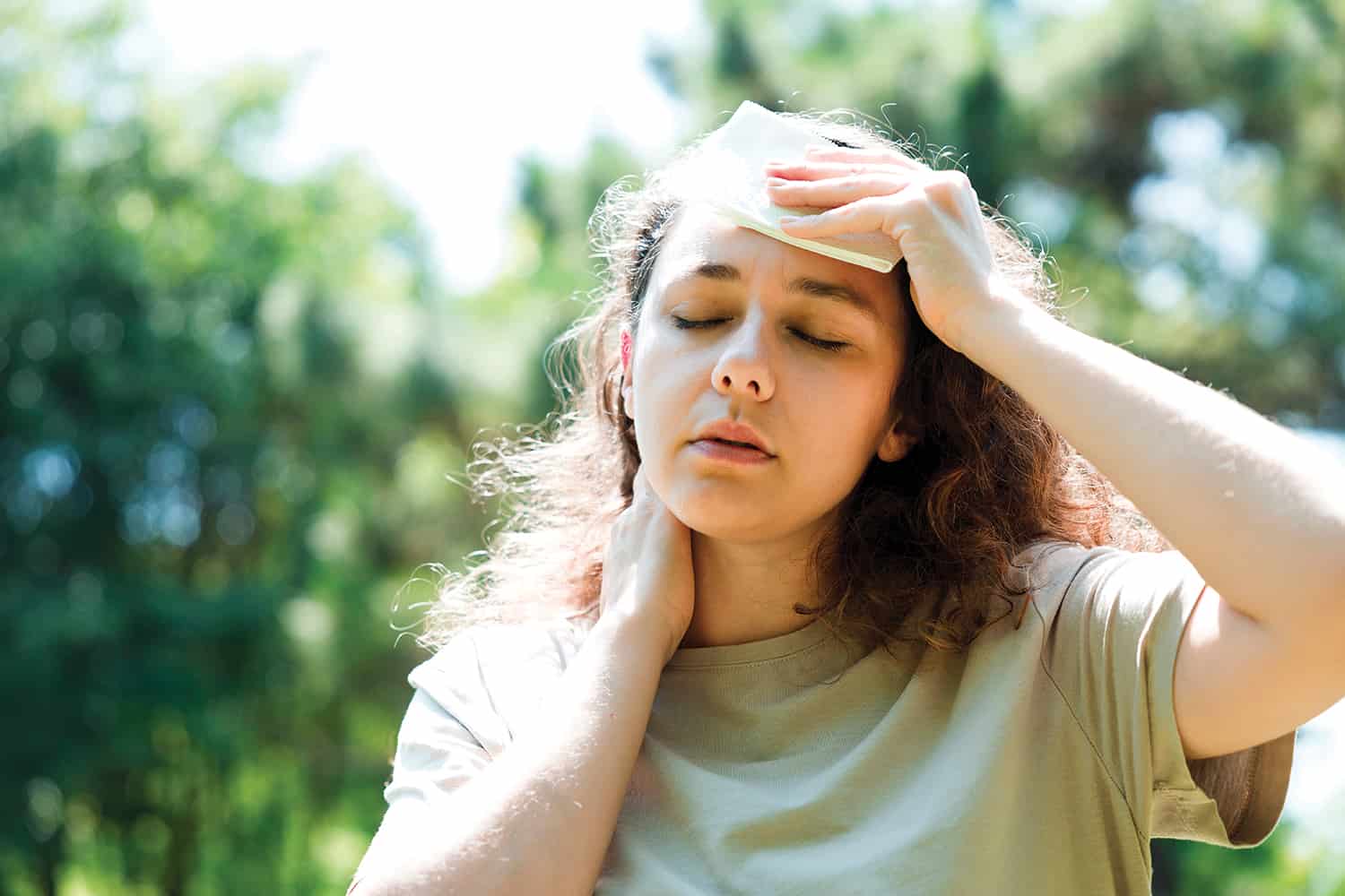 A young woman holding a cold compress to her forehead