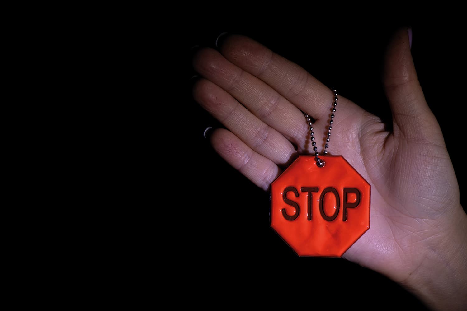 A hand holding a lanyard which is a 'stop' sign