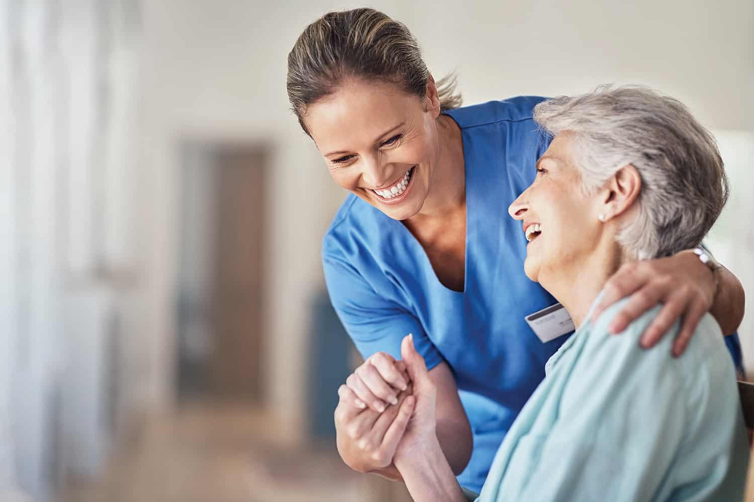 A woman laughing and holding hands with a female nurse