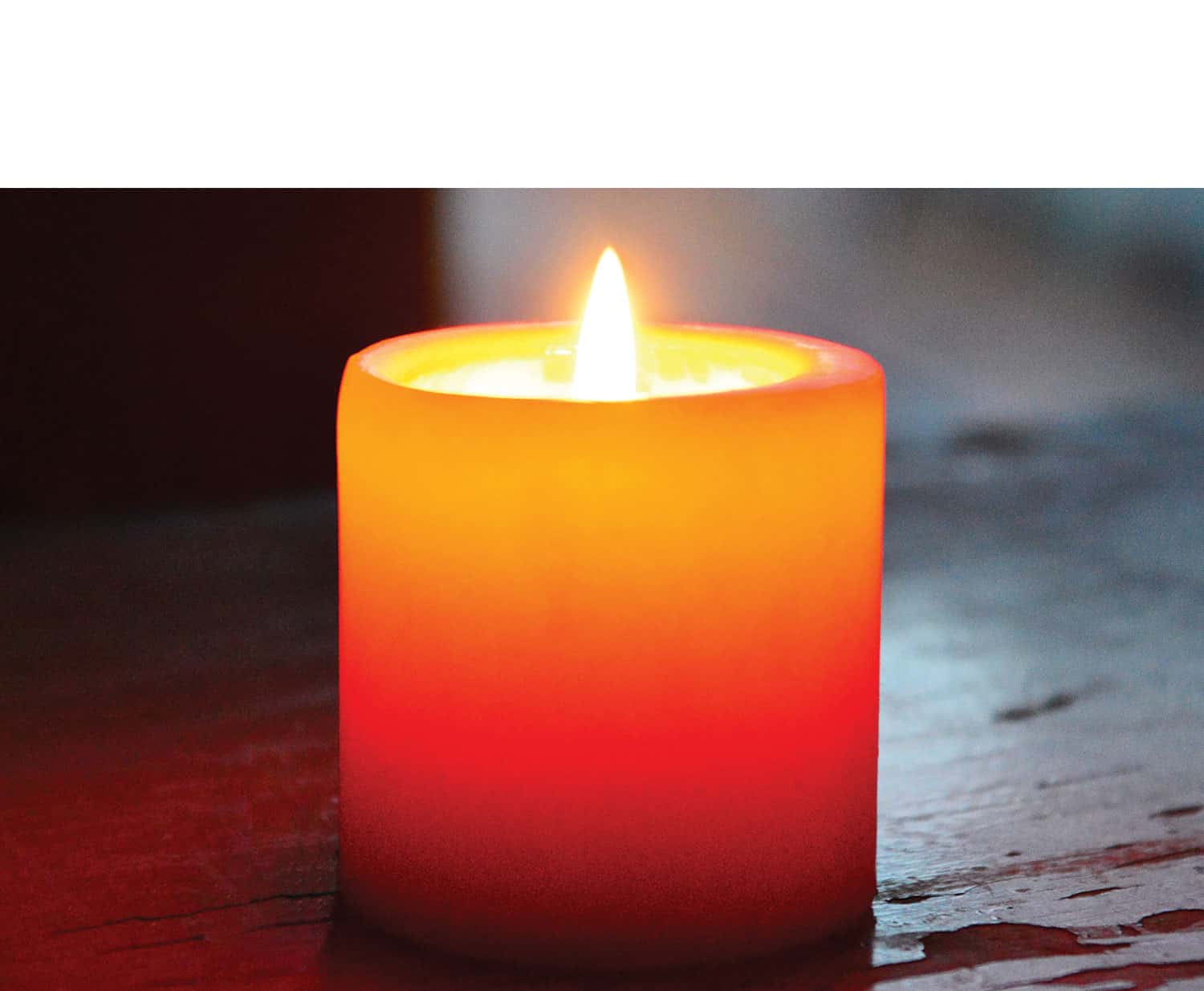 A lit candle on a wooden table